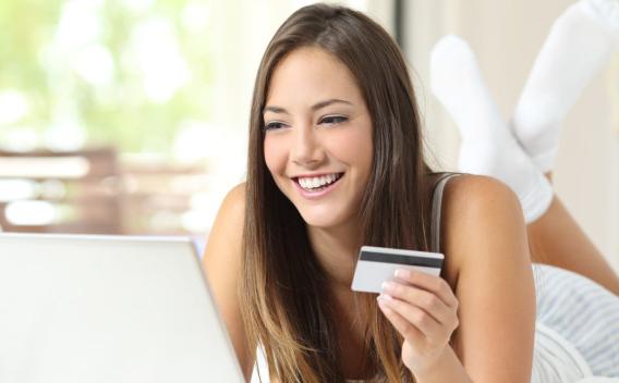 Shopper shopping online with credit card and laptop on the bed at home