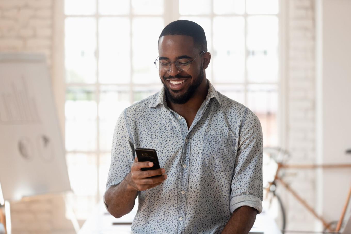 Man smiling while looking at his phone screen