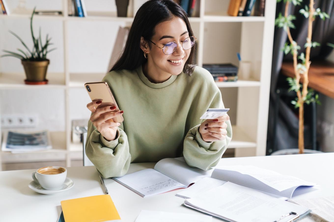Young woman using credit card while holding a smartphone